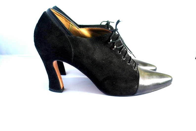 May include: Black suede and leather ankle boots with a lace-up front and a high block heel.