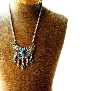 Boho vintage 70s silver tone metal necklace with a large filigree pendant, tassel and faux turquoise.