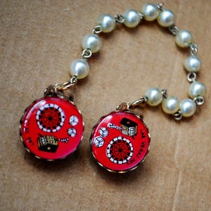 Cadena protectora para cuello, suéter y bufanda, estilo mod, de perla sintética blanca, vintage de 1960, con dos clips de plástico rosa en forma de botón y temática de Las Vegas.