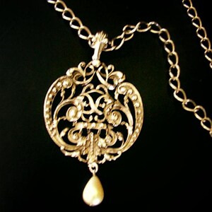 May include: A silver filigree pendant necklace with a pearl drop. The pendant features intricate floral designs and is suspended from a silver chain.