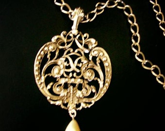 Collier vintage des années 70 en métal argenté avec un gros pendentif rond en filigrane. Fabriqué par Avon