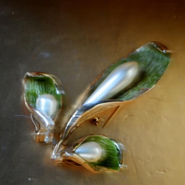 Retro vintage 60s gold tone metal  cala lily parure with a tear drop shape faux pearl as a centerpiece and green background.