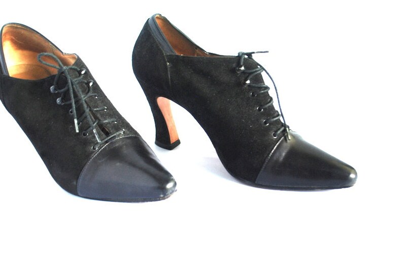 May include: A pair of black suede and leather ankle boots with lace-up fronts and high heels.