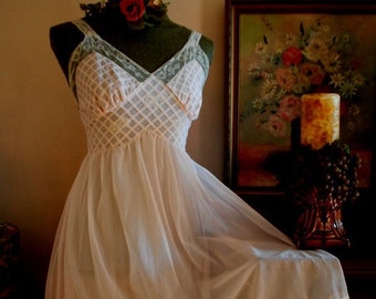 May include: A white sheer slip dress with a delicate lace trim and a pink and white checkered pattern. The dress is on a mannequin with a red rose on the bust.