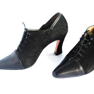 May include: A pair of black suede and leather ankle boots with lace-up fronts and high heels.