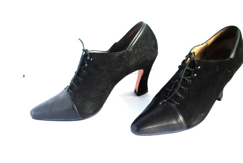 May include: A pair of black suede and leather ankle boots with lace-up fronts and high heels.