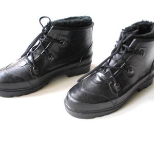 May include: A pair of black rubber boots with faux fur lining. The boots have a lace-up design and a rounded toe. The boots are likely waterproof and suitable for cold weather.