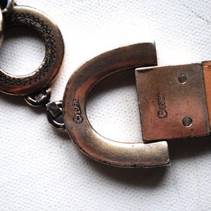 Peut inclure: Une boucle de ceinture argent&eacute;e avec une sangle en cuir. La boucle est en forme de fer &agrave; cheval et porte le texte "&copy;1995" d'un c&ocirc;t&eacute; et "&copy;1995" de l'autre.