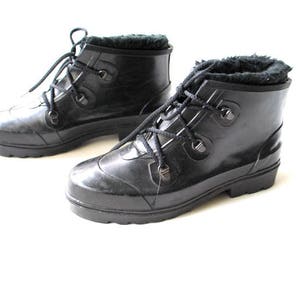 May include: A pair of black waterproof boots with faux fur lining. The boots feature a lace-up design with metal eyelets and a rounded toe. The soles are thick and provide good grip. Designed for cold weather.