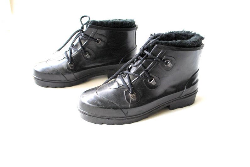 May include: A pair of black waterproof boots with faux fur lining. The boots feature a lace-up design with metal eyelets and a rounded toe. The soles are thick and provide good grip. Designed for cold weather.
