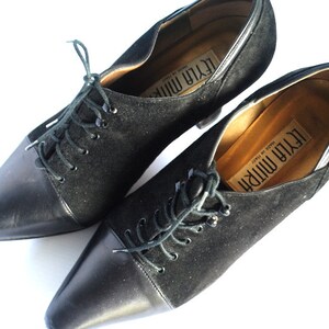 May include: Pair of black suede and leather lace-up shoes with pointed toes and heels. The shoes are labeled "Leyla Mirri" and "Made in Italy".