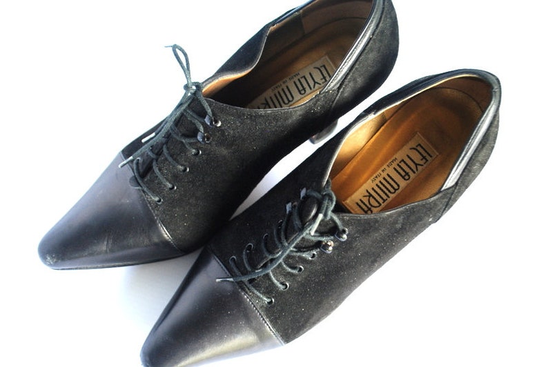 May include: Pair of black suede and leather lace-up shoes with pointed toes and heels. The shoes are labeled "Leyla Mirri" and "Made in Italy".