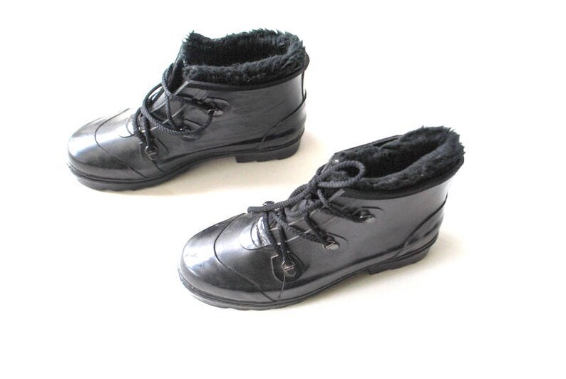 May include: Two black, glossy rain boots with faux fur lining and lace-up fastenings. The boots are displayed on a white background, highlighting their sleek design and practical features for wet weather conditions.