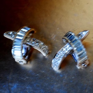 1960 vintage Old Hollywood, silver tone metal clip on earrings, curved X  shape with clear rhinestones and aurora borealis, by Boucher.