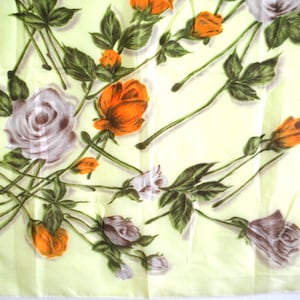 May include: A light green fabric with a floral pattern. The flowers are orange, white, and brown. The fabric has a silky texture.