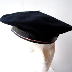 May include: A black beret with a black leather band and a white and red trim.