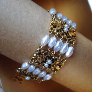 Victorian style vintage 70s,  god tone metal, filigree, wide panels bracelet with a white, faux pear beads between.  Celebrity, New York.