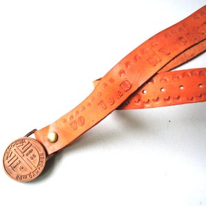 May include: A brown leather keychain with a round metal tag that says "20th CAMPFIRE" and "1988" in a circle. The leather strap has the text "GO TO THE END" embossed on it.