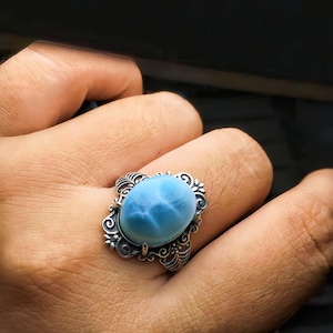 May include: A silver ring with a blue and white gemstone set in a detailed floral design.