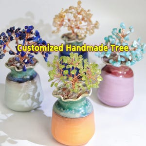 Puede incluir: Cuatro pequeños árboles de piedras preciosas hechos a mano en diferentes colores, cada uno en una maceta de cerámica única. Los árboles están hechos con alambre y varias piedras preciosas, incluyendo azul, verde y marrón. El texto "Árbol hecho a mano personalizado" está superpuesto en la imagen.
