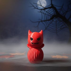 May include: A red devil figurine with a carved face and horns. The Halloween-themed decoration is set against a spooky backdrop of a full moon, bare tree branches, and fog.