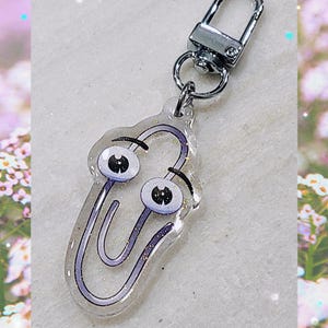 May include: A silver key chain with a clear, glittery, purple paperclip charm with googly eyes.
