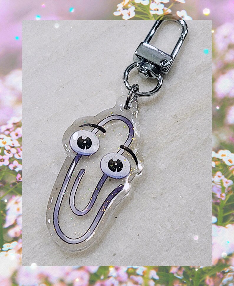 May include: A silver key chain with a clear, glittery, purple paperclip charm with googly eyes.