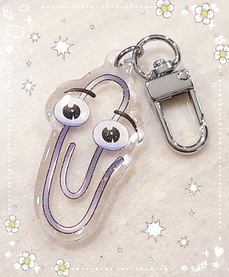 May include: A purple glitter paperclip keychain with googly eyes. The keychain is attached to a silver metal key ring.