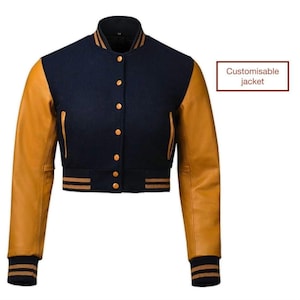 Puede incluir: Una chaqueta de béisbol azul marino y marrón con cierre de botones y ribetes a rayas. La chaqueta tiene mangas largas y un estilo recortado. "Chaqueta personalizable" está escrito en texto blanco sobre un fondo rojo.