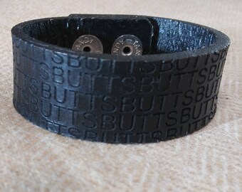 Leather cuff that says BUTTS on it