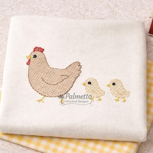 May include: Embroidered white fabric featuring a hen and two chicks. The hen is light brown with a red comb and yellow feet. The chicks are light yellow. A yellow and white checkered fabric is visible.