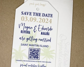 May include: A white save the date card with a blue luggage tag design. The card says "Save the Date" with the date "03.09.2024" and the names "Megan & Eduardo OLIVEIRA MAGAÑA" with the text "are getting married" and "SAINT MARTIN ISLAND". The card also includes a QR code and the text "THEKNOT.COM/OURWEDDING/OLIVEIRA-AND-MAGAÑA" and "formal invitation to follow".