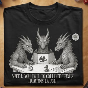 May include: Black t-shirt featuring a detailed illustration of three dragons around a table, playing a game. The text "NAT 1: YOU FAIL TO COLLECT TAXES. HUMANS LAUGH." is printed below the image. Dice and game pieces are also visible.