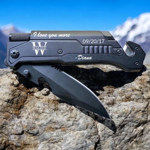 May include: Black multi-tool with a knife blade, a bottle opener, and a seatbelt cutter. The tool has a personalized inscription that reads "I love you more" and "Walter" with a date and "Diana".