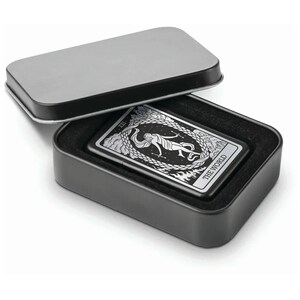 May include: A black metal lighter with a silver design of the World tarot card. The lighter is in a black tin box with a black velvet lining.