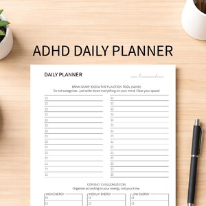 Puede incluir: Un planificador diario para el TDAH con el título "ADHD DAILY PLANNER" en la parte superior. El planificador incluye secciones para un planificador diario, un "brain dump" y una categorización contextual. Un bolígrafo negro está a la derecha.
