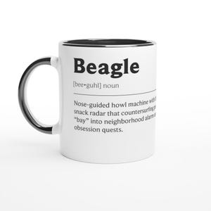Peut inclure: Une tasse en céramique blanche avec un bord et une anse noirs. La tasse présente le mot "Beagle" en lettres noires en gras, ainsi qu'une définition humoristique d'un beagle. Le texte est centré sur la surface de la tasse.
