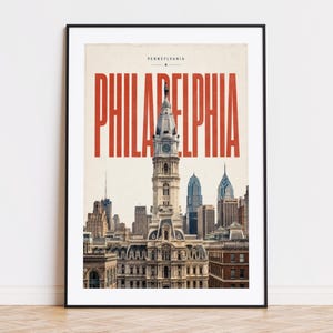 Könnte beinhalten: Gerahmter Kunstdruck mit einer Stadtansicht von Philadelphia, Pennsylvania. Das Bild zeigt die Skyline der Stadt, mit dem Wort "PHILADELPHIA" in großen, roten Buchstaben. Der Druck befindet sich in einem schwarzen Rahmen.
