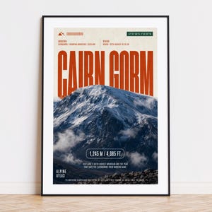 May include: A framed poster featuring a mountain landscape with the text "CAIRN GORM" in large orange letters. The poster includes the mountain's elevation: 1,245 meters / 4,085 feet. The poster is in a black frame.