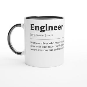 Könnte beinhalten: Weißer Keramikbecher mit schwarzem Griff und Rand. Der Becher zeigt das Wort "Engineer" in fetten schwarzen Buchstaben zusammen mit einer Definition. Die Definition enthält die Phrase "Problemlöser" und "Klebeband".