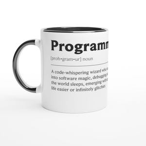 Op de afbeelding: Witte keramische mok met een zwarte binnenkant en handvat. De mok toont het woord "Programmer" in vette zwarte letters, samen met een definitie. De definitie beschrijft een code-fluisterende tovenaar.