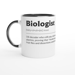 Pode incluir: Caneca de cerâmica branca com alça e borda pretas. A caneca apresenta a palavra "Biologist" em letras pretas em negrito, juntamente com uma definição. A definição inclui a pronúncia e uma descrição humorística do trabalho de um biólogo.