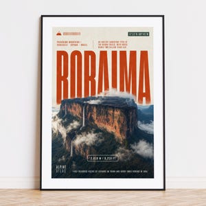 Può includere: Un poster incorniciato con una fotografia del Monte Roraima, un altopiano di arenaria in Sud America. Il poster presenta la parola "RORAIMA" in grandi lettere arancioni. Il poster include l'altitudine della montagna, 2.810 m, e il testo "Alpine Atlas".