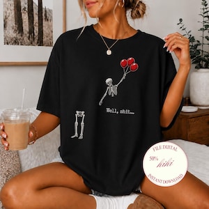 May include: A black short-sleeve t-shirt featuring a graphic of a skeleton torso holding three red balloons with its hand and a separate skeleton leg section below. The text "Well, shit..." is printed in white below the skeleton torso.