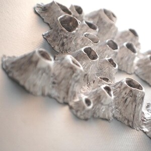 Puede incluir: Una escultura de cer&aacute;mica blanca con una superficie texturizada que se asemeja al coral. La escultura tiene m&uacute;ltiples formas redondeadas y huecas, creando un dise&ntilde;o &uacute;nico y org&aacute;nico.