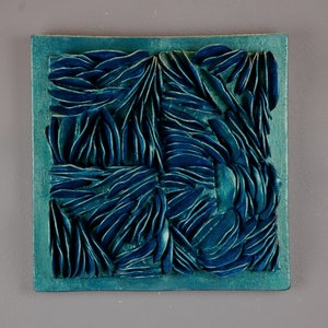May include: A teal blue square wall art piece with a raised, textured design of overlapping, organic shapes.