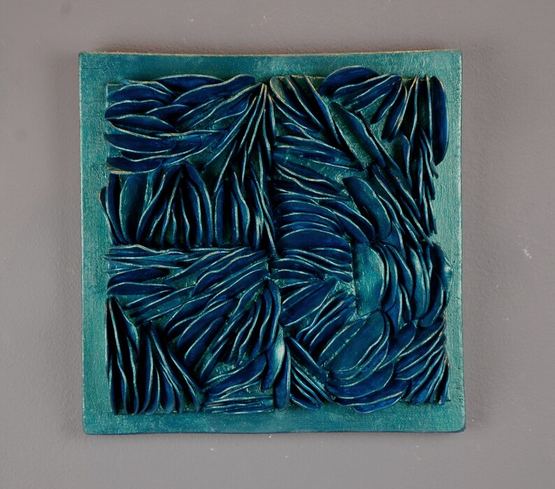 May include: A teal blue square wall art piece with a raised, textured design of overlapping, organic shapes.