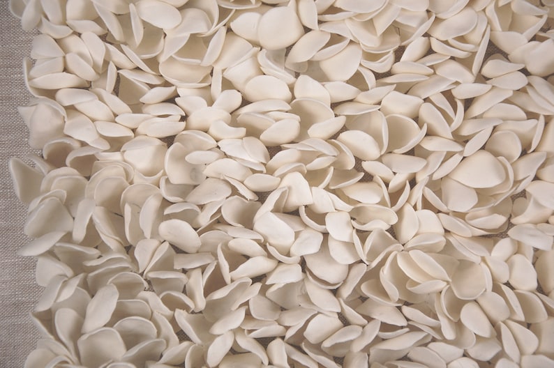 May include: A close-up of a white, textured fabric with a pattern of small, overlapping, petal-like shapes.