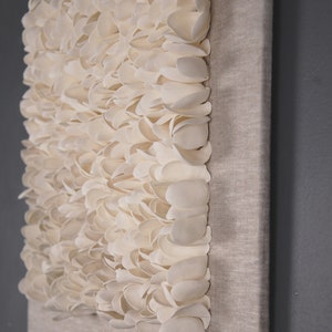 May include: A white canvas wall art piece with a textured surface made of many small, white, petal-like shapes.