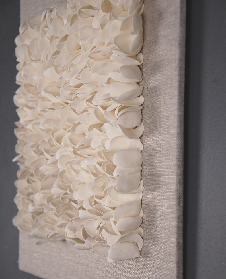 May include: A white canvas wall art piece with a textured surface made of many small, white, petal-like shapes.